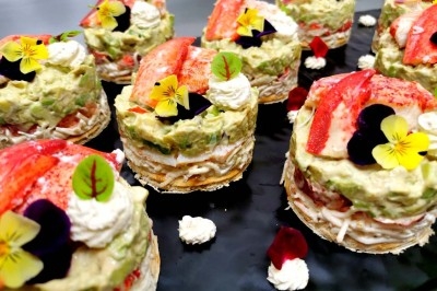 Plateau de fromages variés entourés de grappes de raisin, noix et herbes fraîches sur une table claire.