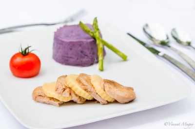 Plateau de fromages variés entourés de grappes de raisin, noix et herbes fraîches sur une table claire.