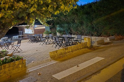 Salle de restaurant lumineuse avec tables dressées, chaises modernes et grandes fenêtres donnant sur un espace vert.