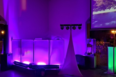 Un couple en tenue de mariage danse dans une salle éclairée par des lumières colorées et entourée de fumée.