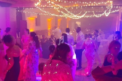 Des personnes dansent sous des guirlandes lumineuses dans une salle éclairée par des lumières colorées.