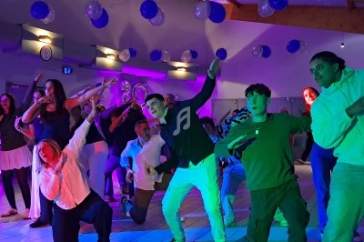 Des personnes dansent et posent de manière expressive dans une salle décorée de ballons et éclairée par des lumières…