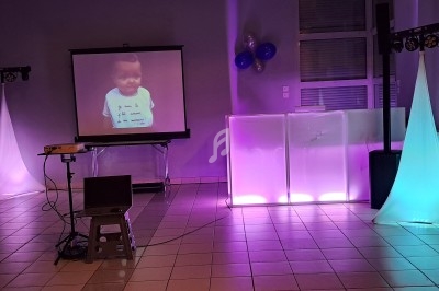 Salle décorée avec des lumières colorées, un projecteur affichant l'image d'un enfant et un ordinateur portable sur une…