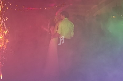 Un couple danse au milieu d'une piste entourée de fumée colorée et de gerbes d'étincelles.