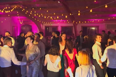 Homme debout devant un ordinateur portable, dans une salle éclairée par des lumières bleues, avec une projection en arrière…