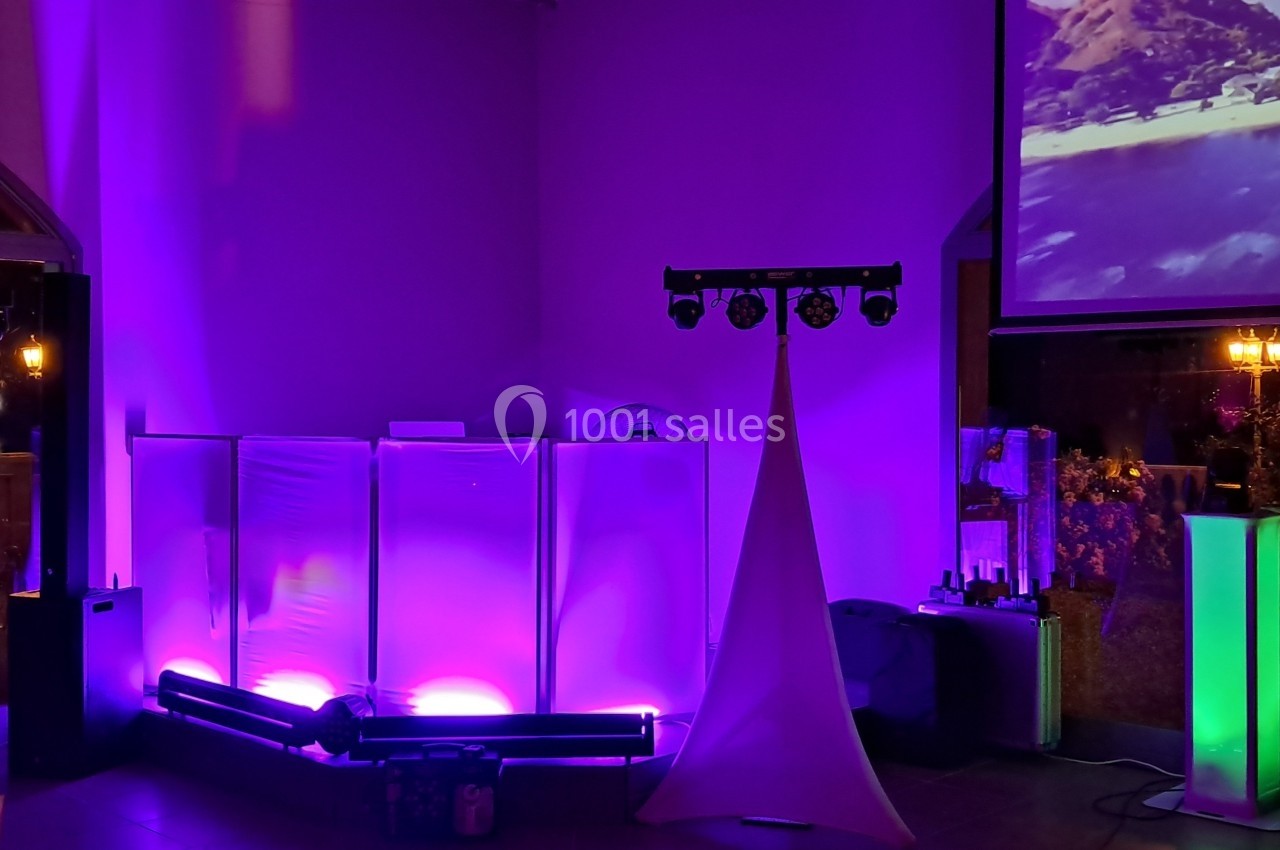 Équipement de sonorisation et éclairage coloré installé dans une salle avec un écran projetant une image de plage.