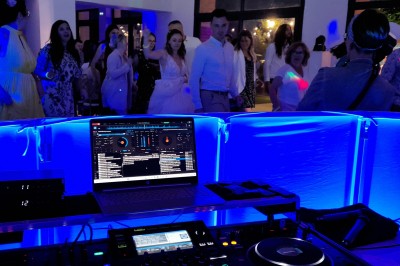 Homme debout devant un ordinateur portable, dans une salle éclairée par des lumières bleues, avec une projection en arrière…