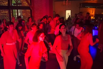 Homme debout devant un ordinateur portable, dans une salle éclairée par des lumières bleues, avec une projection en arrière…