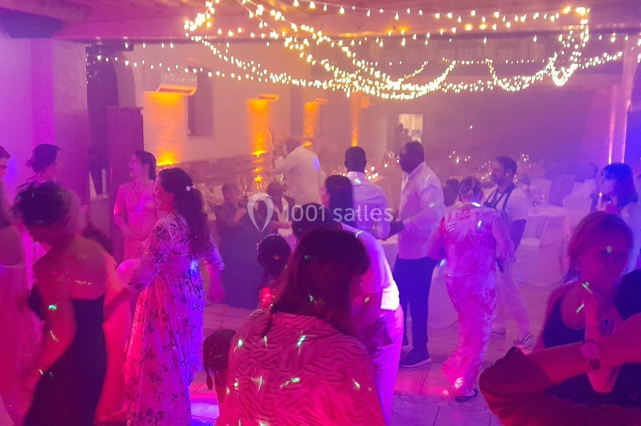 Personnes dansant sous des guirlandes lumineuses dans une ambiance festive avec éclairages colorés.