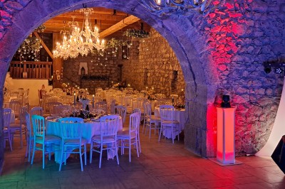 Homme debout devant un ordinateur portable, dans une salle éclairée par des lumières bleues, avec une projection en arrière…