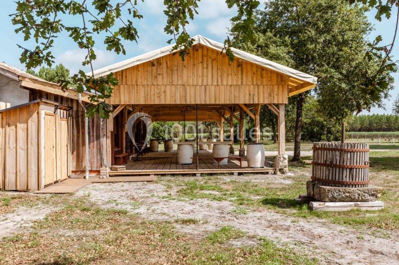 Abri en bois ouvert avec des tonneaux à l'intérieur, entouré d'arbres et situé dans un environnement naturel.