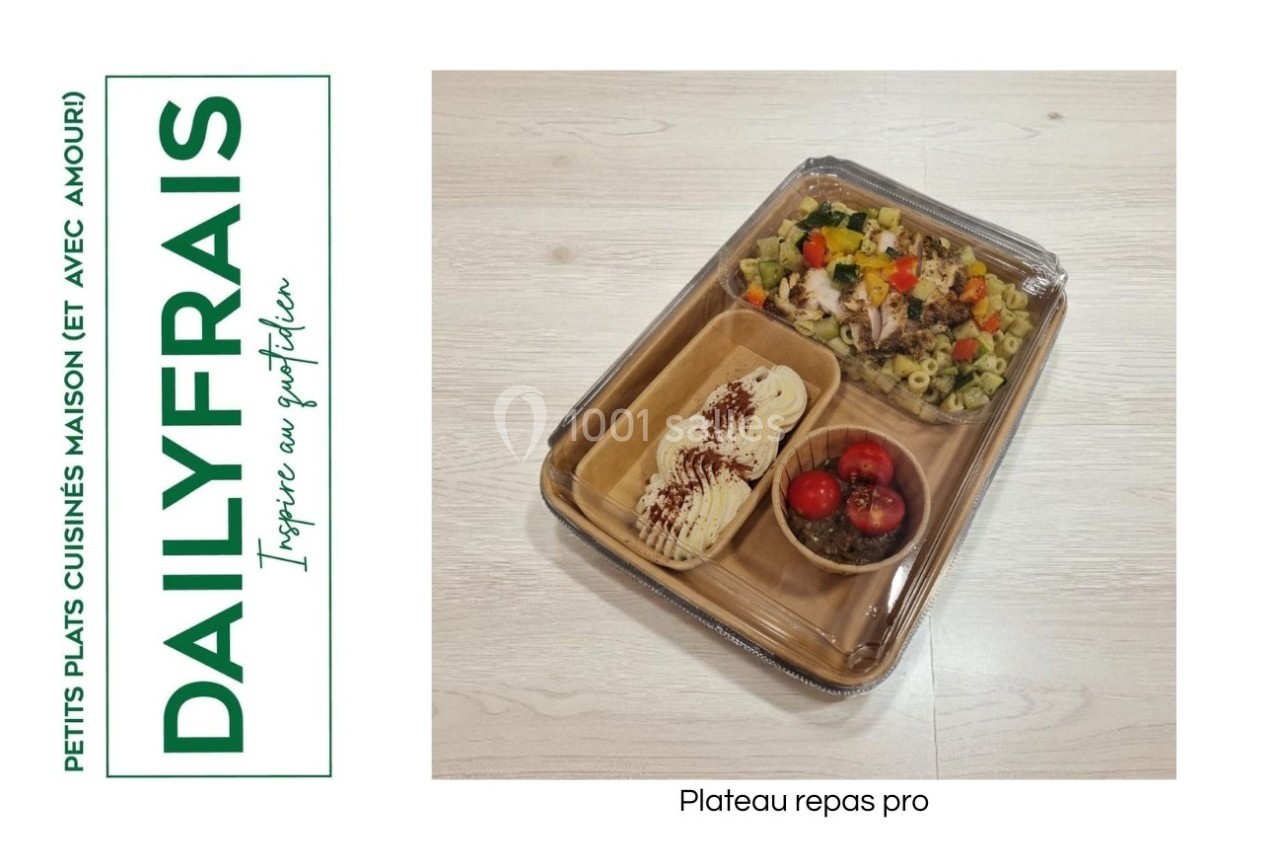 Plateau repas contenant des pâtes, des légumes, des tomates cerises et un dessert, présenté sur une table claire.