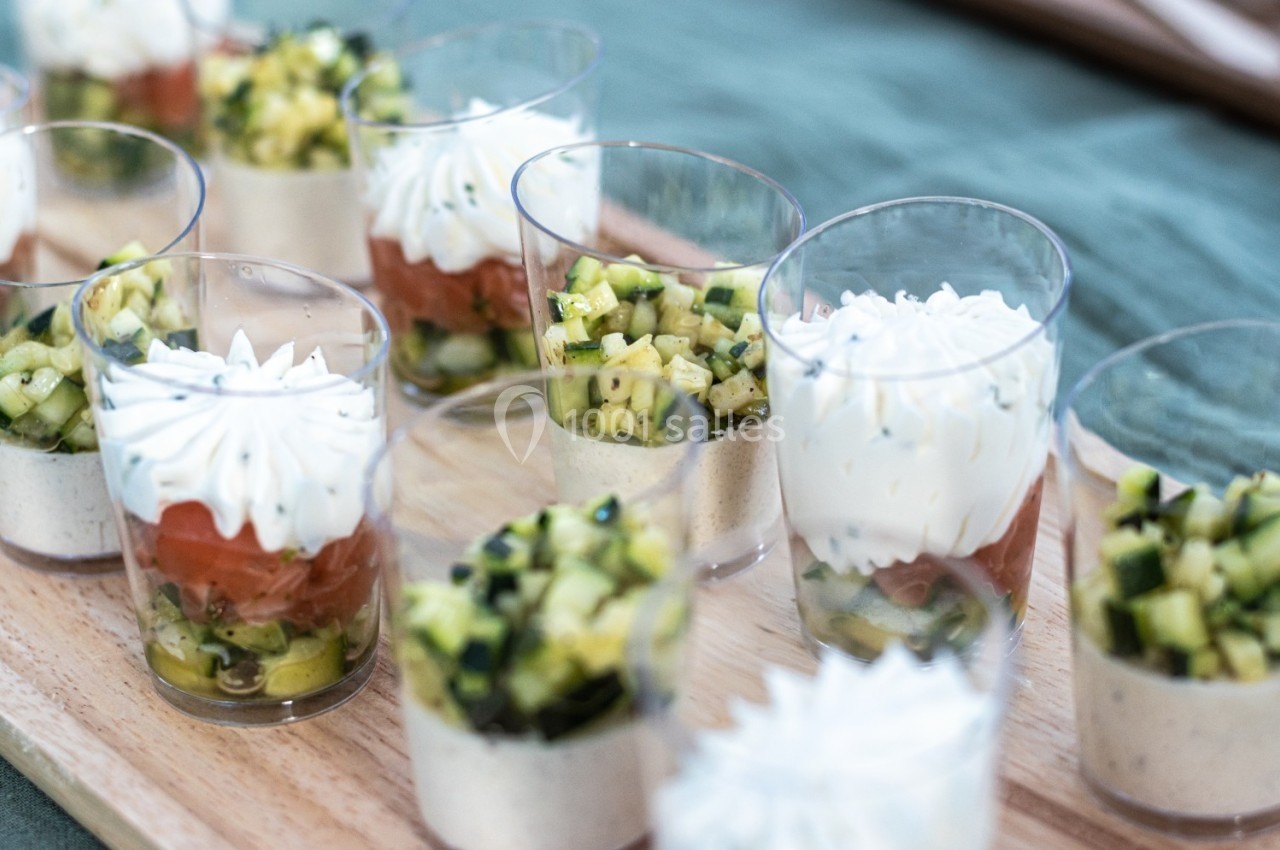 Verrines composées de légumes, saumon et crème fouettée, disposées sur un plateau en bois.