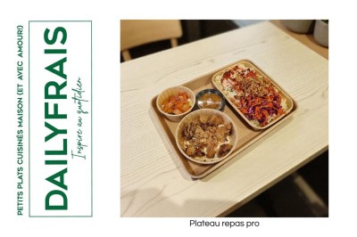 Plateau repas composé de légumes colorés, viande, riz et accompagnements, présenté sur une table en bois clair.