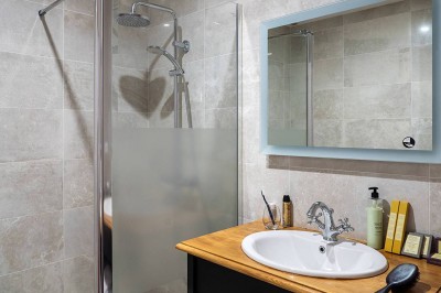 Salle de bain moderne avec douche à l'italienne, lavabo sur plan en bois, miroir éclairé et porte-serviettes mural.