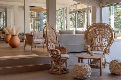 Piscine extérieure entourée de chaises longues et de tables, avec des bâtiments blancs et des arbres en arrière-plan.