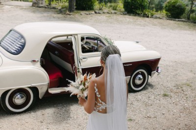 Centre de table floral coloré avec des roses et des verres disposés sur une nappe blanche, bougie en arrière-plan.
