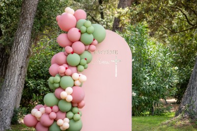 Salle de réception décorée pour un mariage, avec tables dressées, chandeliers suspendus et poutres apparentes au plafond.