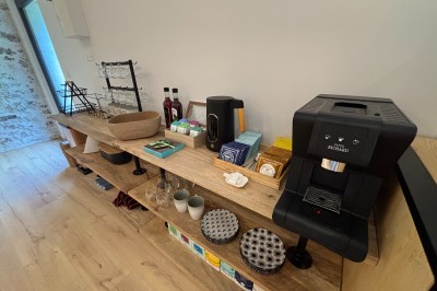 Salle spacieuse avec parquet clair, murs blancs, poutres apparentes et grandes baies vitrées donnant sur un jardin.