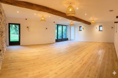 Miniature Location salle Verdelot (Seine-et-Marne) - Maison la Girouette #6 Salle lumineuse avec parquet en bois clair, murs blancs, poutres apparentes et grandes fenêtres donnant sur un jardin.