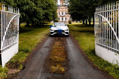 Un couple en tenue de mariage se tient devant une grande table décorée, avec un manoir en arrière-plan.