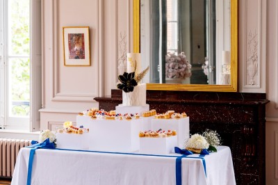 Un couple en tenue de mariage se tient devant une grande table décorée, avec un manoir en arrière-plan.