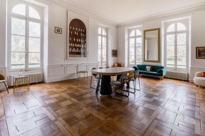 Un couple en tenue de mariage se tient devant une grande table décorée, avec un manoir en arrière-plan.