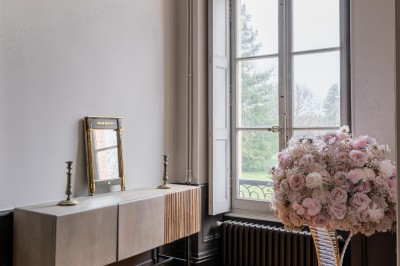 Un couple en tenue de mariage se tient devant une grande table décorée, avec un manoir en arrière-plan.