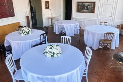 Un couple en tenue de mariage se tient devant une grande table décorée, avec un manoir en arrière-plan.