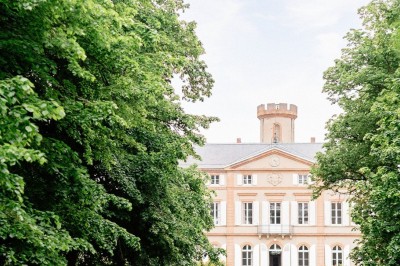 Un couple en tenue de mariage se tient devant une grande table décorée, avec un manoir en arrière-plan.