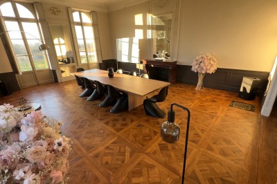 Un couple en tenue de mariage se tient devant une grande table décorée, avec un manoir en arrière-plan.