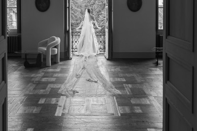 Tente blanche montée sur une pelouse, entourée de personnes et de tables, dans une cour avec bâtiments en arrière-plan.