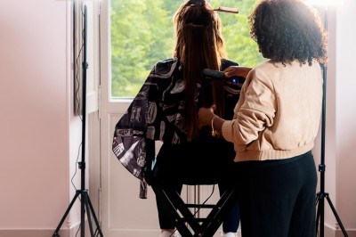 Tente blanche montée sur une pelouse, entourée de personnes et de tables, dans une cour avec bâtiments en arrière-plan.