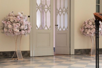 Tente blanche montée sur une pelouse, entourée de personnes et de tables, dans une cour avec bâtiments en arrière-plan.