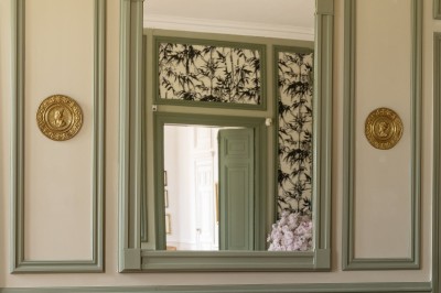 Tente blanche montée sur une pelouse, entourée de personnes et de tables, dans une cour avec bâtiments en arrière-plan.