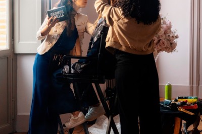 Tente blanche montée sur une pelouse, entourée de personnes et de tables, dans une cour avec bâtiments en arrière-plan.