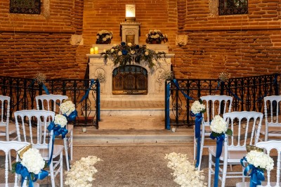 Tente blanche montée sur une pelouse, entourée de personnes et de tables, dans une cour avec bâtiments en arrière-plan.