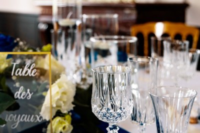 Tente blanche montée sur une pelouse, entourée de personnes et de tables, dans une cour avec bâtiments en arrière-plan.