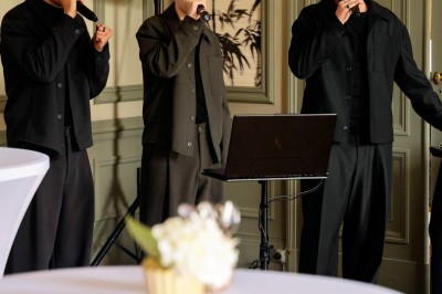Tente blanche montée sur une pelouse, entourée de personnes et de tables, dans une cour avec bâtiments en arrière-plan.