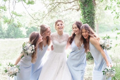 Tente blanche montée sur une pelouse, entourée de personnes et de tables, dans une cour avec bâtiments en arrière-plan.