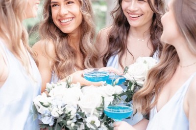 Tente blanche montée sur une pelouse, entourée de personnes et de tables, dans une cour avec bâtiments en arrière-plan.