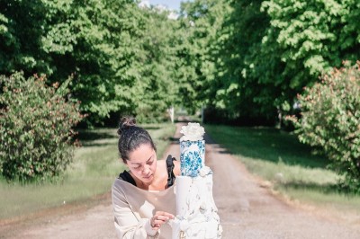 Tente blanche montée sur une pelouse, entourée de personnes et de tables, dans une cour avec bâtiments en arrière-plan.
