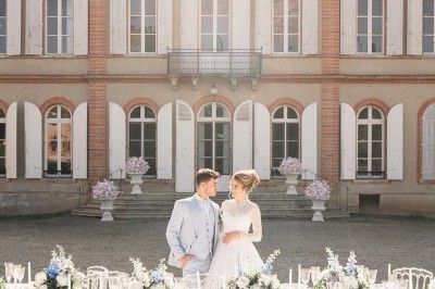 Tente blanche montée sur une pelouse, entourée de personnes et de tables, dans une cour avec bâtiments en arrière-plan.