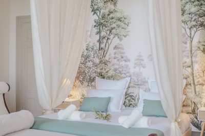 Tente blanche montée sur une pelouse, entourée de personnes et de tables, dans une cour avec bâtiments en arrière-plan.