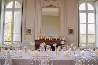 Tente blanche montée sur une pelouse, entourée de personnes et de tables, dans une cour avec bâtiments en arrière-plan.