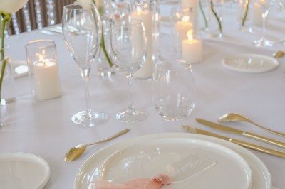 Tente blanche montée sur une pelouse, entourée de personnes et de tables, dans une cour avec bâtiments en arrière-plan.