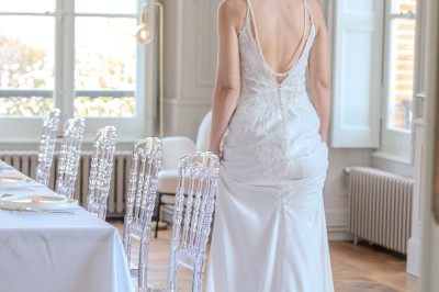 Tente blanche montée sur une pelouse, entourée de personnes et de tables, dans une cour avec bâtiments en arrière-plan.
