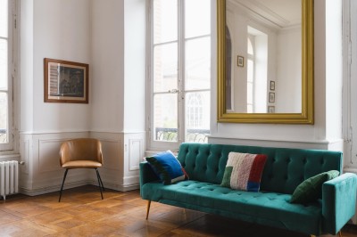 Tente blanche montée sur une pelouse, entourée de personnes et de tables, dans une cour avec bâtiments en arrière-plan.