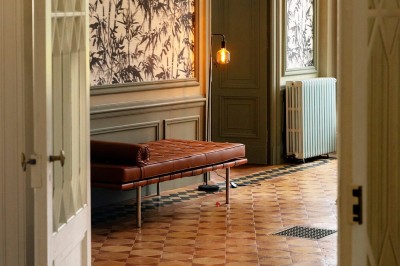 Tente blanche montée sur une pelouse, entourée de personnes et de tables, dans une cour avec bâtiments en arrière-plan.