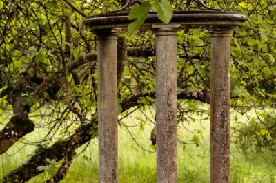 Tente blanche montée sur une pelouse, entourée de personnes et de tables, dans une cour avec bâtiments en arrière-plan.